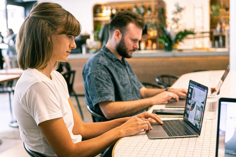 a girl and a boy designing logo using laptop